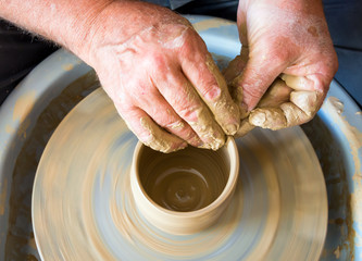 Fototapeta na wymiar The master forms a clay cup on a potter's wheel