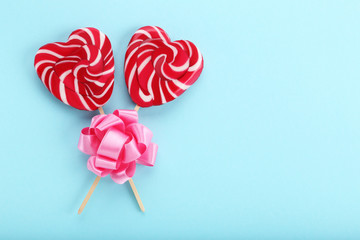 Heart shaped lollipops with ribbon bow on blue background