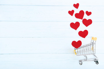 Shopping cart with red hearts on wooden table
