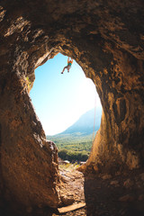 Rock climber climbs into the cave.