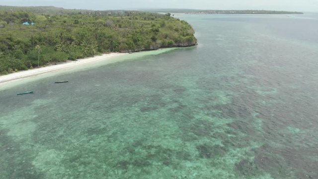 Aerial: Flying over tropical beach turquoise water coral reef , Tomia island Wakatobi National Park Indonesia Maldives Polynesia white sand beach. Native cinelike D-log color profile