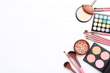 Makeup brushes with palette on white wooden table