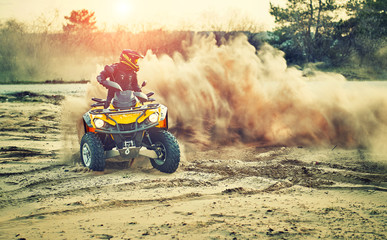 Teen riding ATV in sand dunes making a turn in the sand