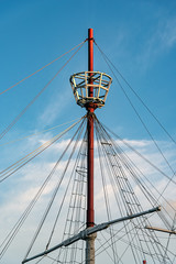 Mast of a ship with its ropes, its tail for the watch and a beautiful cloudy sky behind