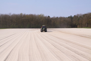 ROERMOND, NETHERLANDS - MARCH 30. 2019: Chalk fertilizer application by tractor with spreader to...
