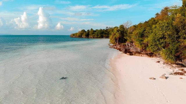 Aerial slow motion: woman walking on tropical island turquoise water white sand beach, Tomia Island, Wakatobi marine national park, Indonesia, teal orange grading