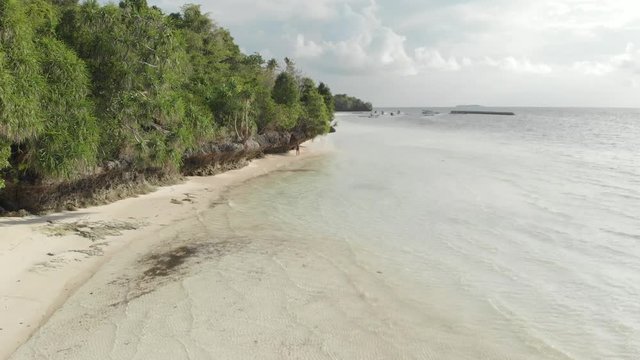 Aerial: woman walking on tropical island turquoise water white sand beach, Tomia Island, Wakatobi marine national park, Indonesia, Native cinelike D-log color profile