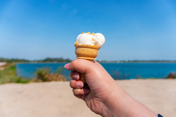 Hand with ice cream on blurred blue sky nature background