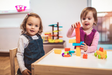 Obraz na płótnie Canvas Children toddlers girls play toys at home, kindergarten or nursery.