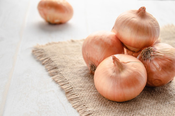 Fresh onion on wooden background and on burlap. Ripe onions Allium cepa or onions or vegetarian and vegan food.