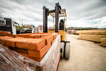 Fototapeta na wymiar Fork lifter carry construction material clay bricks at the warehouse building site