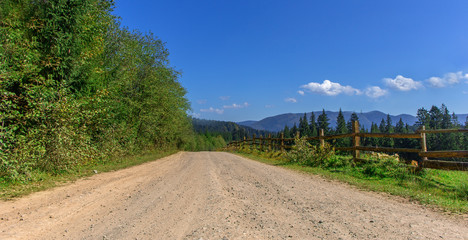 Fototapeta na wymiar country road in the mountains and a wooden fence