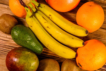 Still life with exotic fruits. Bananas, mango, oranges, avocado, grapefruit and kiwi fruits on wooden table. Top view