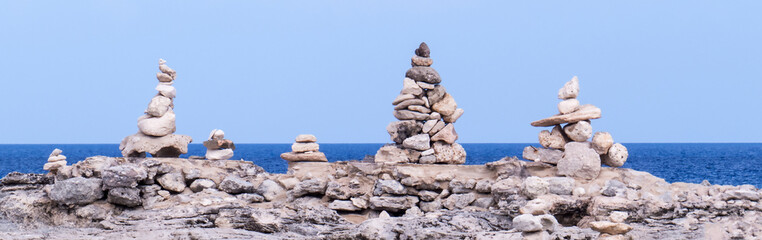 Panoramic photo of many sculptures of stacked rocks in front of the Atlantic Ocean.