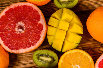 Still life with exotic fruits. Mango, oranges, grapefruit and kiwi fruits on wooden table. Top view