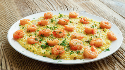 Fototapeta na wymiar fried scampi with saffron risotto decorated with parmesan, parsley and pink pepper 