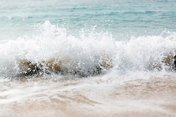 Powerful blue wave breaks along the shore. Close up