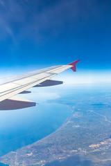 Aircraft wing on the clouds, flies on the city background