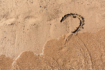 Question mark sign on sand beach near the sea. Concept of dilemma, answer and question