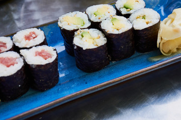 sushi rolls on a blue plate with vegetarian and salmon rolls on a silver table of the restaurant