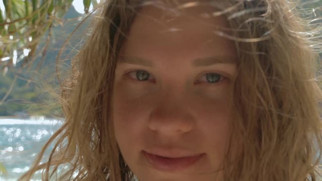 Close-up gimbal shot of beautiful european young woman on tropical beach looking in the camera