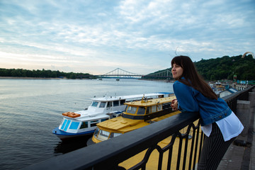 Fototapeta premium young pretty woman looking on river at morning time. boats in dock