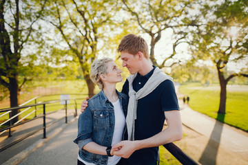 Fototapeta premium stylish and beautiful woman with short light hair, dressed in a blue jeans jacket walks with her handsome man in a sunny large city