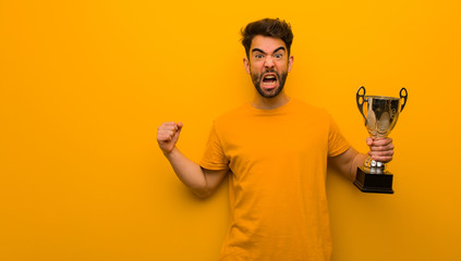 Young man holding a trophy screaming very angry and aggressive