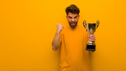 Young man holding a trophy screaming very angry and aggressive