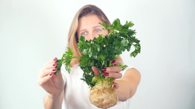 Defocused young woman showing fresh celery root