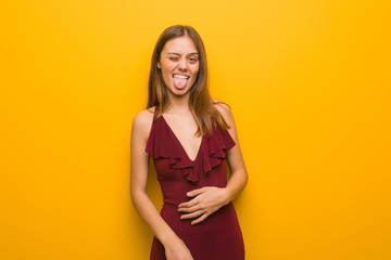 Young elegant woman wearing a dress funnny and friendly showing tongue