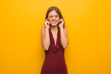 Young elegant woman wearing a dress covering ears with hands