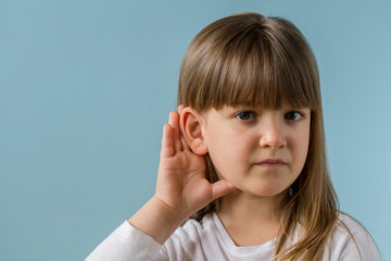 Little girl with hearing problem on light blue background. Close up, copy space.