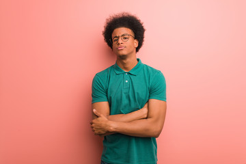 Young african american man over a pink wall crossing arms relaxed