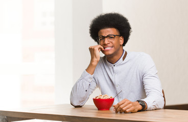Fototapeta na wymiar Young black man having a breakfast biting nails, nervous and very anxious