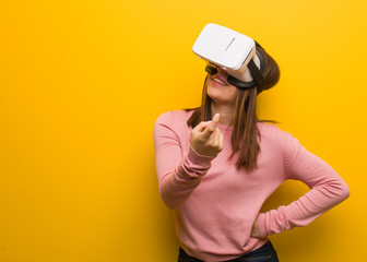 Young cute woman wearing a virtual reality googles inviting to come