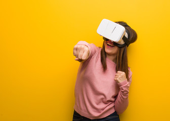 Young cute woman wearing a virtual reality googles showing fist to front, angry expression