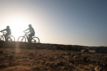 Fototapeta na wymiar Couple of elderly athletes man and woman bicycling along the cliff. Freedom and healthy lifestyles