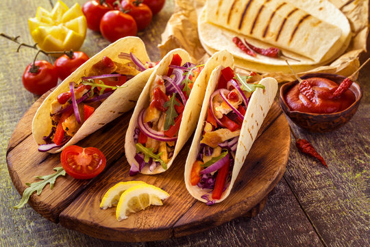 tacos  Mexican food with chicken, pepper, tomatoes, cabbage and salsa on a wooden Board