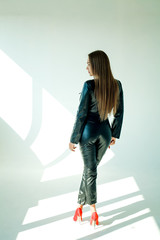long-haired model in a leather jumpsuit on a white background