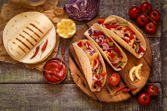 tacos  Mexican food with chicken, pepper, tomatoes, cabbage and salsa on a wooden Board