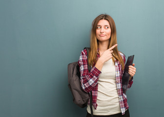 Young student russian woman pointing to the side with finger