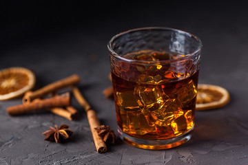 Glass of brandy or whiskey, spices and decorations on dark background. Seasonal holidays concept.