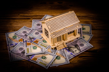 Plywood model of the house and one hundred dollar banknotes. Loan, real estate concept