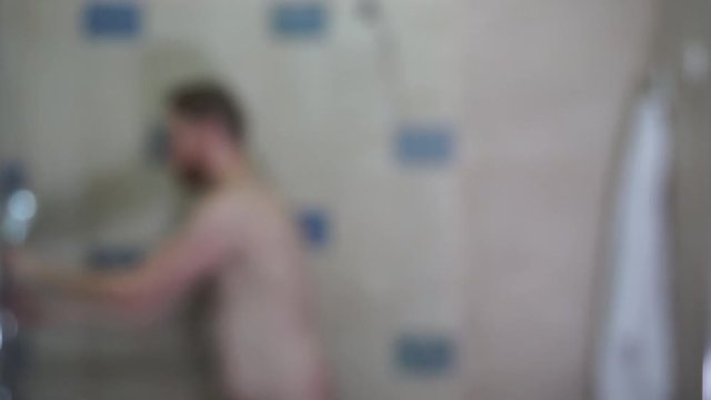 Unrecognizable young man takes off the towel and takes a shower blur video