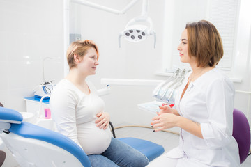 Fototapeta premium positive pregnant woman in dentist office, consultation with young woman dentist. dental treatment for pregnant women