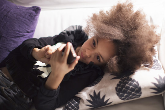 Girl lying on sofa using smartphone