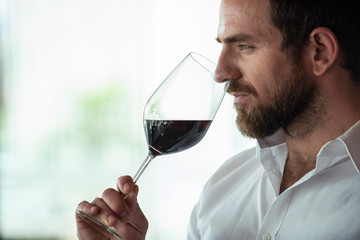Thoughtful mid adult man smelling red wine in bar