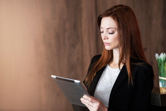 Mid adult businesswoman using digital tablet while standing at hotel reception desk