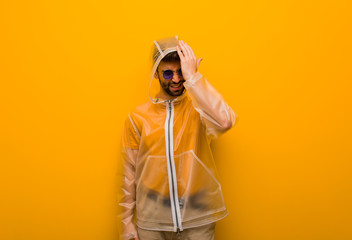 Young man wearing a rain coat forgetful, realize something © Asier